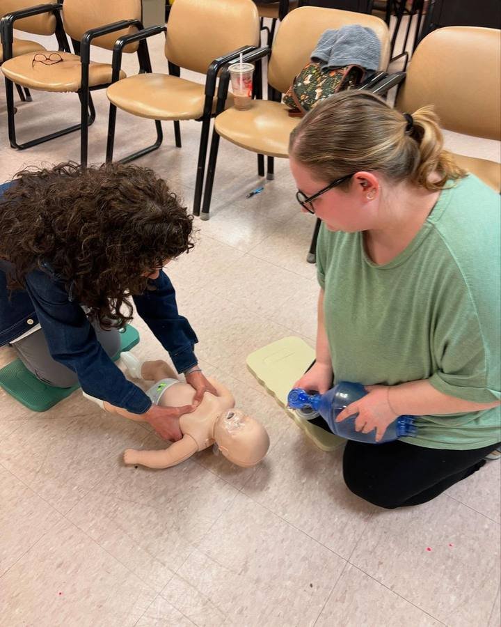 Instructor demonstrating infant CPR on a training mannequin